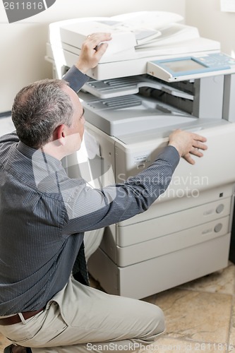 Image of Man opening photocopier in office