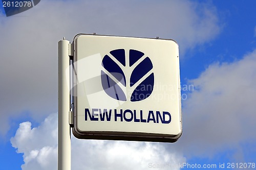 Image of New Holland Sign against Blue Sky with Some Clouds