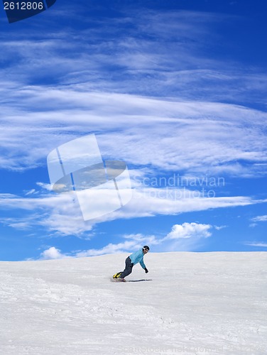 Image of Snowboarder on ski slope and blue sky with clouds