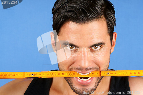 Image of Carpenter worker biting a wooden metric ruler