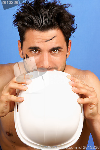 Image of Dirty manual worker biting hard hat