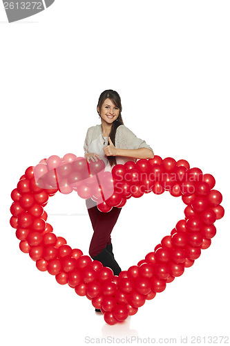 Image of Smiling woman holding red balloon heart