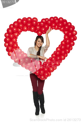 Image of Smiling woman holding red balloon heart