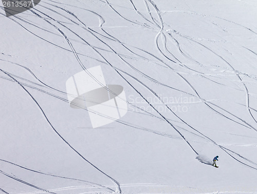 Image of Snowboarder downhill on off piste slope with newly-fallen snow