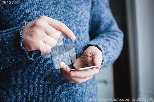 Image of The man is using a smartphone. Modern mobile phone in hand.