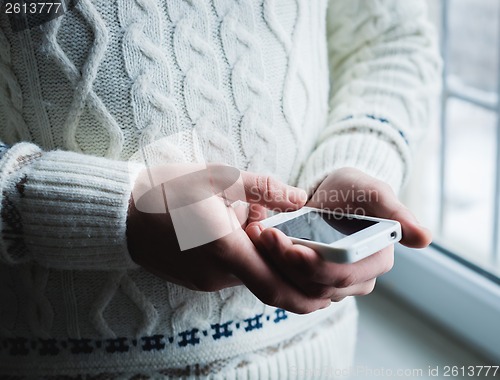 Image of The man is using a smartphone. Modern mobile phone in hand.
