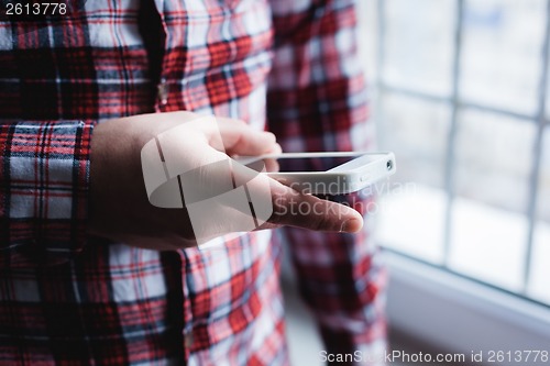 Image of The man is using a smartphone. Modern mobile phone in hand.