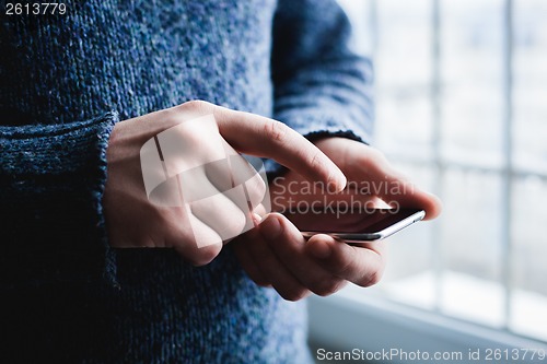 Image of The man is using a smartphone. Modern mobile phone in hand.