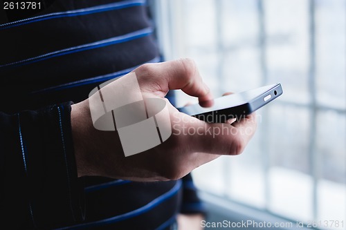 Image of The man is using a smartphone. Modern mobile phone in hand.