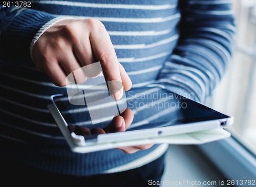 Image of The man uses a tablet PC. Modern gadget in hand.