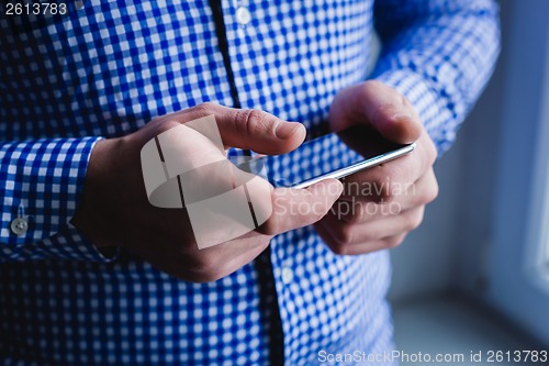 Image of The man is using a smartphone. Modern mobile phone in hand.