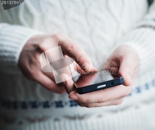 Image of The man is using a smartphone. Modern mobile phone in hand.