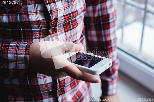 Image of The man is using a smartphone. Modern mobile phone in hand.