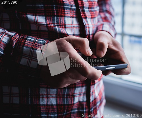 Image of The man is using a smartphone. Modern mobile phone in hand.