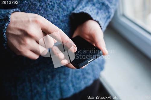 Image of The man is using a smartphone. Modern mobile phone in hand.
