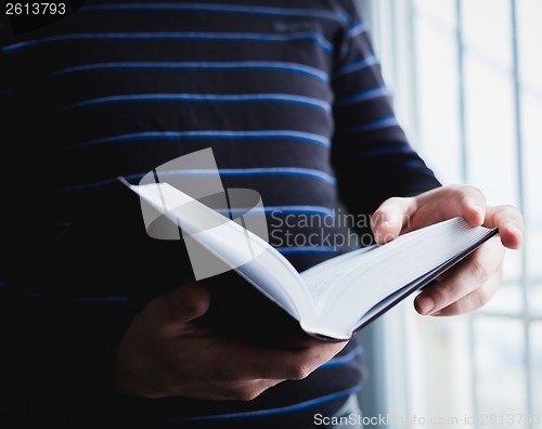 Image of Man reading. Book in his hands.