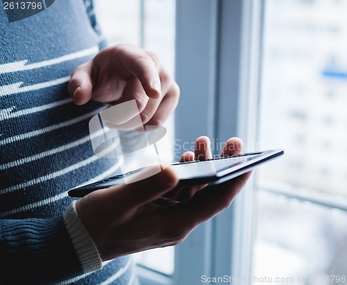 Image of The man is using a smartphone. Modern mobile phone in hand.