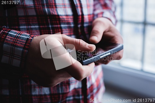Image of The man is using a smartphone. Modern mobile phone in hand.