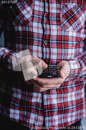 Image of The man is using a smartphone. Modern mobile phone in hand.