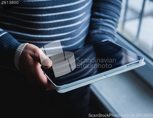 Image of The man uses a tablet PC. Modern gadget in hand.