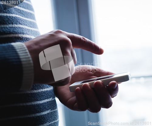 Image of The man is using a smartphone. Modern mobile phone in hand.
