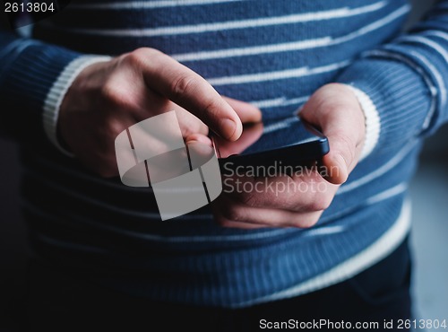 Image of The man is using a smartphone. Modern mobile phone in hand.