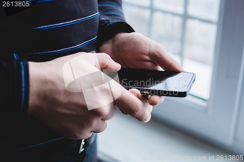 Image of The man is using a smartphone. Modern mobile phone in hand.