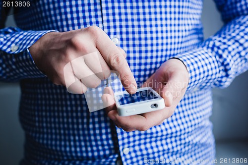 Image of The man is using a smartphone. Modern mobile phone in hand.