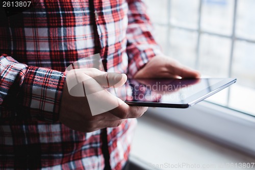 Image of The man uses a tablet PC. Modern gadget in hand.
