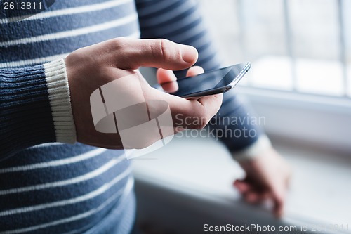 Image of The man is using a smartphone. Modern mobile phone in hand.