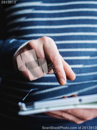 Image of The man uses a tablet PC. Modern gadget in hand.