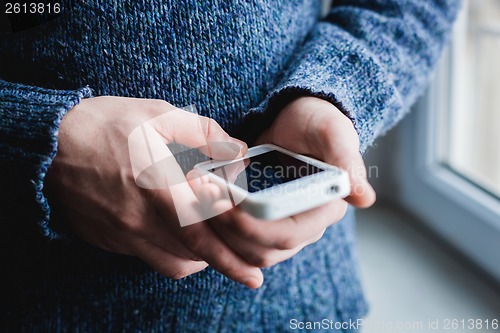 Image of The man is using a smartphone. Modern mobile phone in hand.