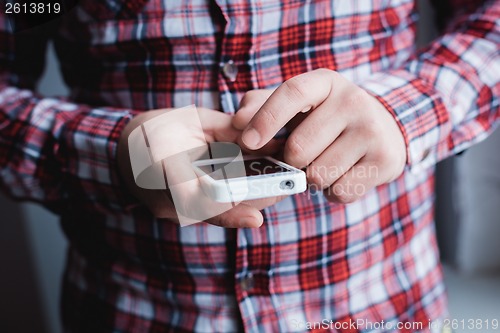 Image of The man is using a smartphone. Modern mobile phone in hand.