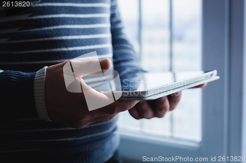 Image of The man uses a tablet PC. Modern gadget in hand.