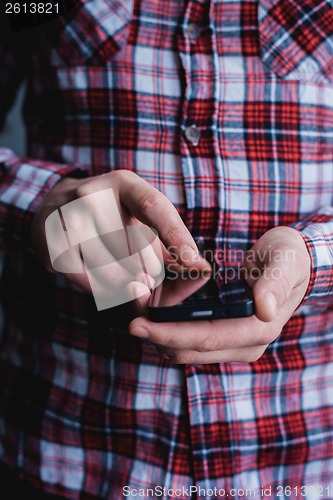 Image of The man is using a smartphone. Modern mobile phone in hand.