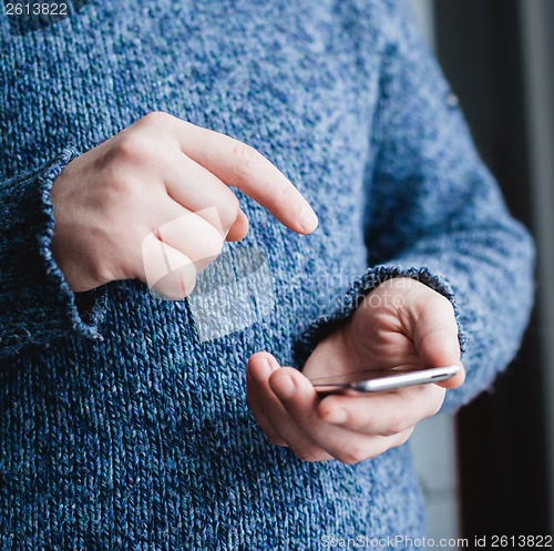 Image of The man is using a smartphone. Modern mobile phone in hand.
