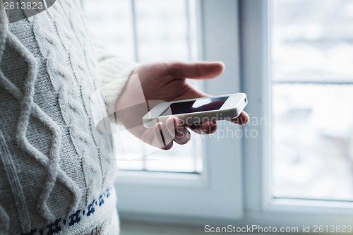 Image of The man is using a smartphone. Modern mobile phone in hand.