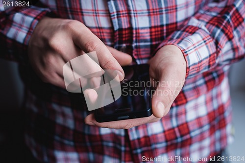 Image of The man is using a smartphone. Modern mobile phone in hand.