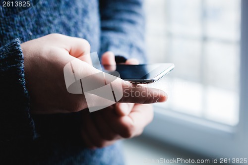 Image of The man is using a smartphone. Modern mobile phone in hand.