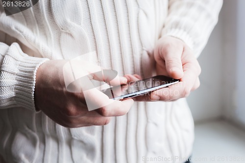 Image of The man is using a smartphone. Modern mobile phone in hand.