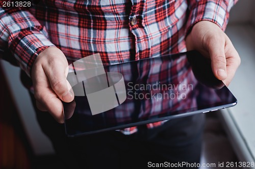 Image of The man uses a tablet PC. Modern gadget in hand.