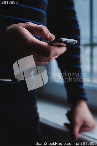 Image of The man is using a smartphone. Modern mobile phone in hand.
