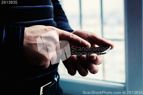 Image of The man is using a smartphone. Modern mobile phone in hand.