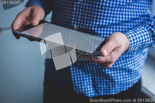 Image of The man uses a tablet PC. Modern gadget in hand.