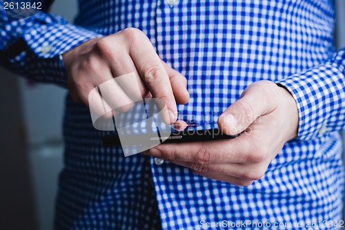Image of The man is using a smartphone. Modern mobile phone in hand.