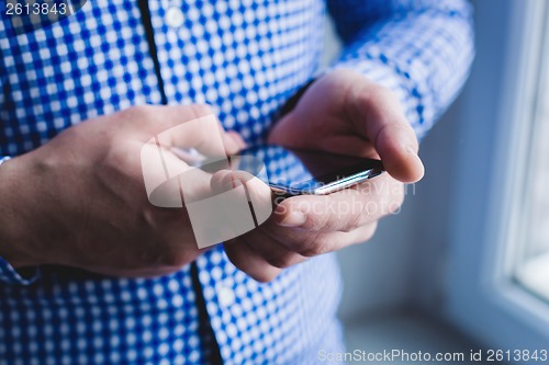 Image of The man is using a smartphone. Modern mobile phone in hand.