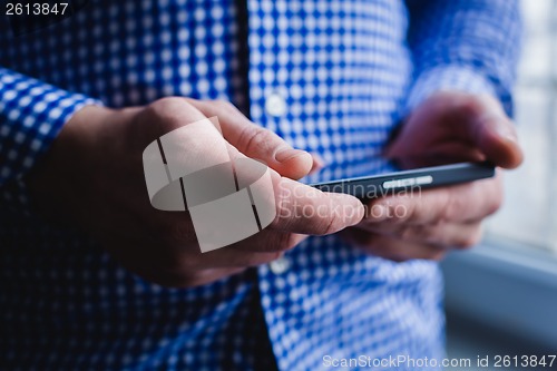 Image of The man is using a smartphone. Modern mobile phone in hand.