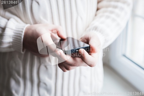 Image of The man is using a smartphone. Modern mobile phone in hand.