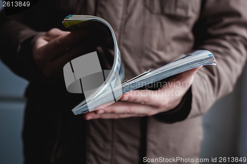 Image of A man looks at a magazine. Press hands.