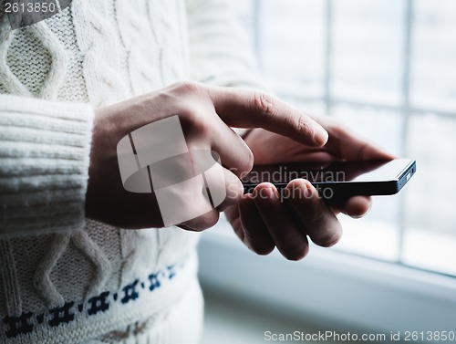 Image of The man is using a smartphone. Modern mobile phone in hand.